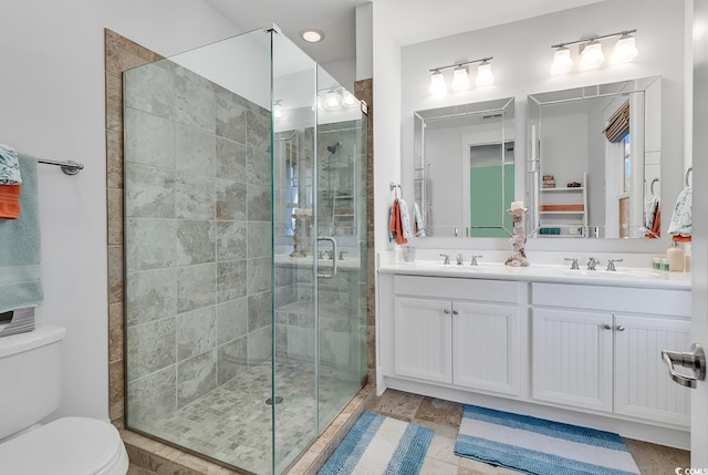 bathroom featuring a sink, a stall shower, toilet, and double vanity