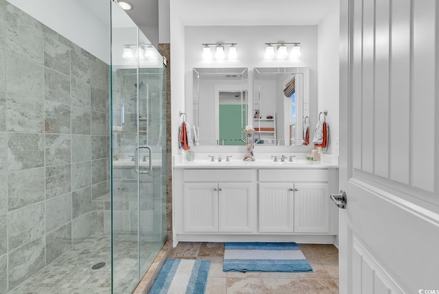 bathroom featuring double vanity, a shower stall, and a sink