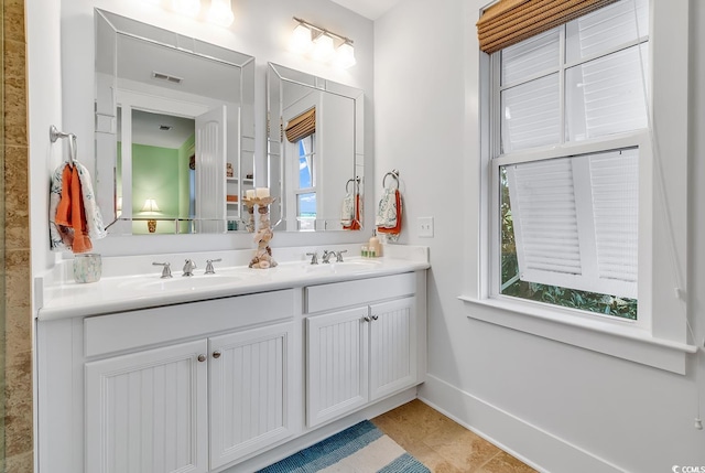 full bathroom featuring double vanity, baseboards, a sink, and tile patterned floors