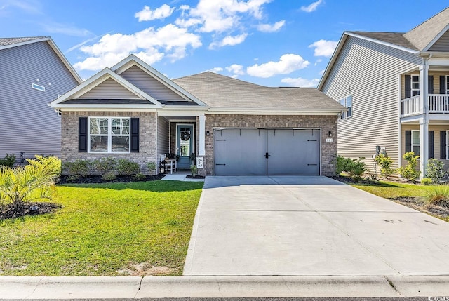 craftsman-style house featuring brick siding, driveway, a front lawn, and a garage