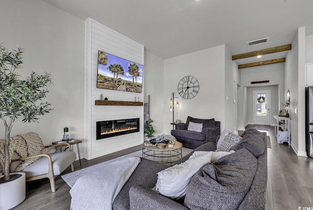 living room featuring baseboards, visible vents, a large fireplace, and wood finished floors