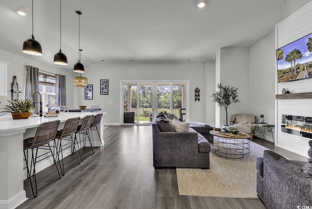 living room with recessed lighting, dark wood finished floors, and a glass covered fireplace