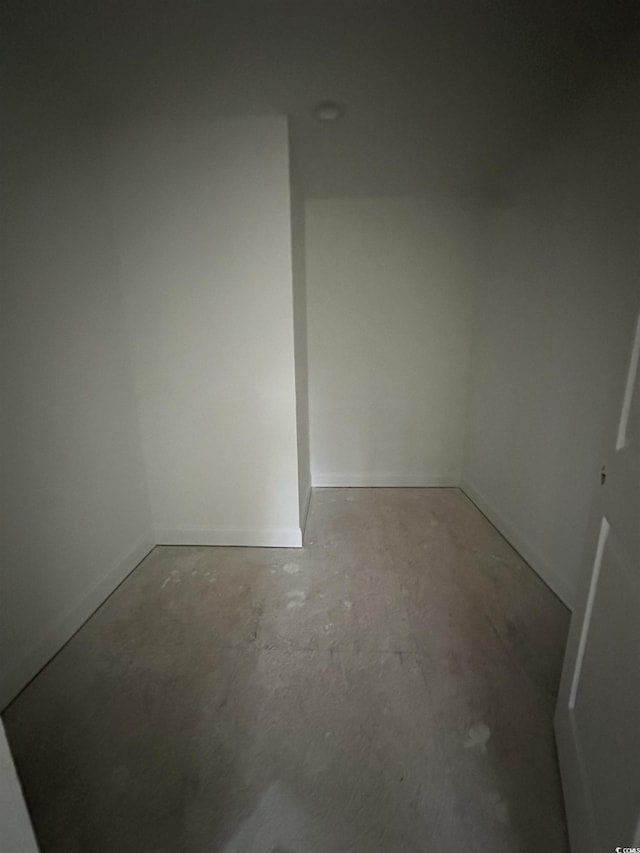 unfurnished room with unfinished concrete floors and baseboards
