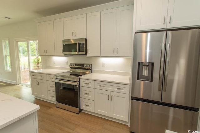 2212 Dykman Cir, Little River, SC 29566 - kitchen with stainless steel appliances, light wood-type flooring, white cabinetry, and light stone countertops
