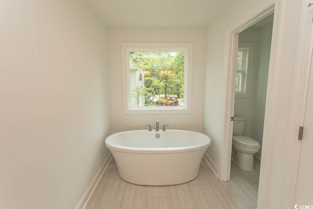 2212 Dykman Cir, Little River, SC 29566 - bathroom featuring a soaking tub, toilet, plenty of natural light, and baseboards