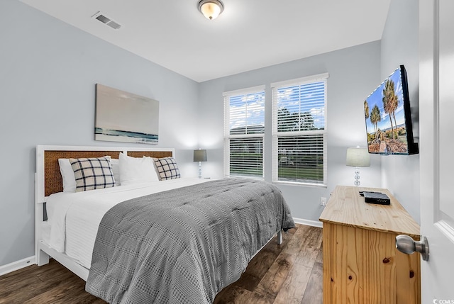 bedroom with baseboards, visible vents, and wood finished floors