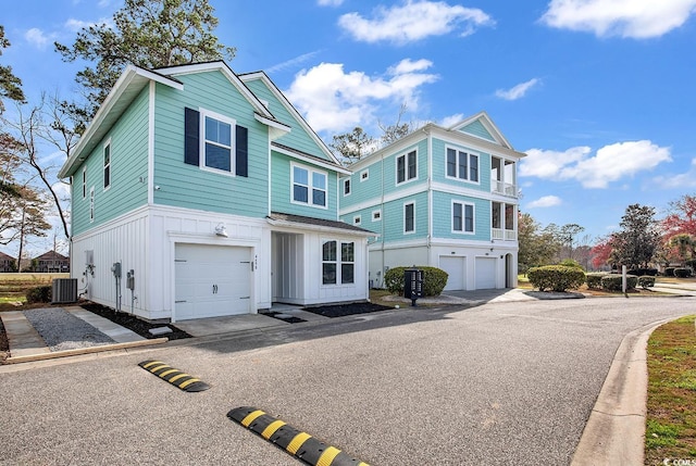 view of front facade with board and batten siding, an attached garage, and central AC unit