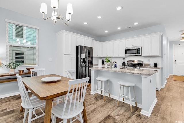 kitchen featuring white cabinetry, appliances with stainless steel finishes, an island with sink, and visible vents