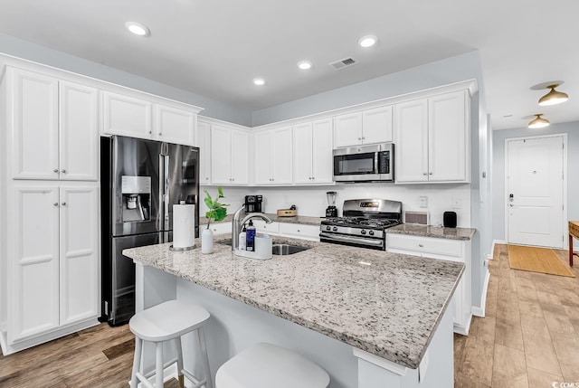 kitchen with visible vents, a sink, white cabinets, and stainless steel appliances