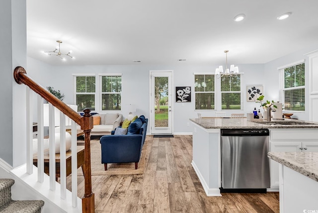 kitchen with a notable chandelier, a sink, white cabinetry, light wood-type flooring, and stainless steel dishwasher