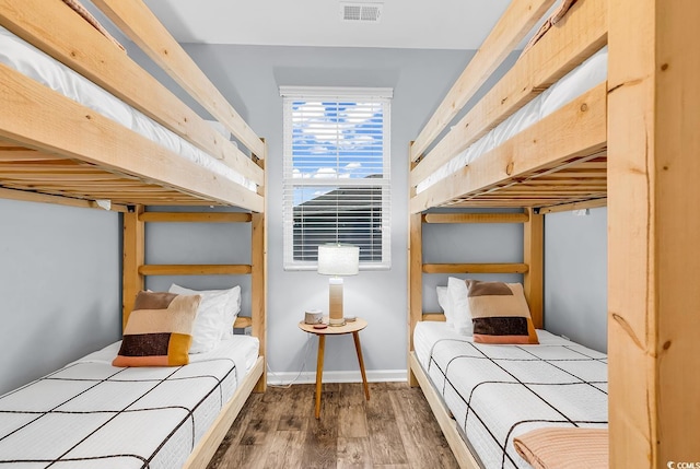 bedroom with baseboards, wood finished floors, and visible vents