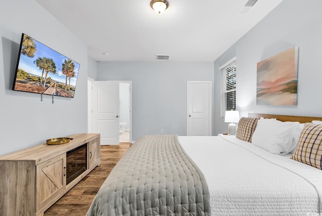 bedroom with dark wood-type flooring, connected bathroom, and visible vents