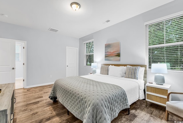bedroom featuring multiple windows, wood finished floors, and visible vents