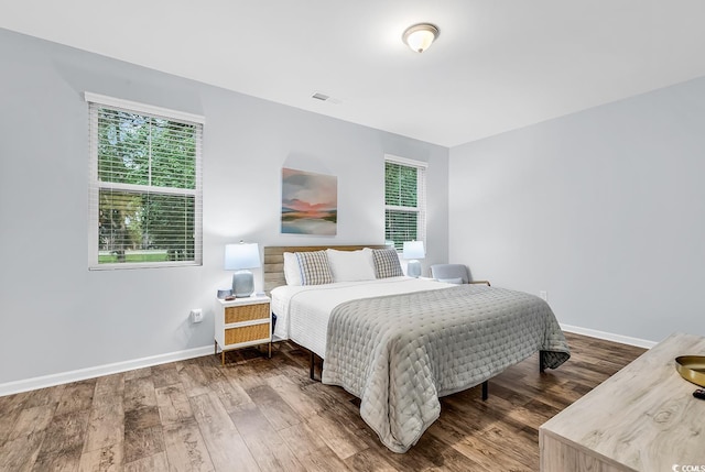 bedroom with baseboards, wood finished floors, and visible vents
