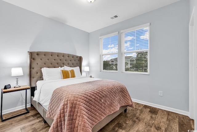 bedroom with baseboards, wood finished floors, and visible vents