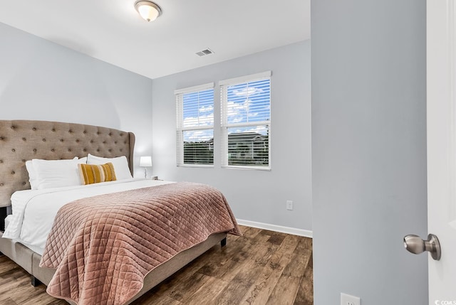 bedroom featuring baseboards, wood finished floors, and visible vents