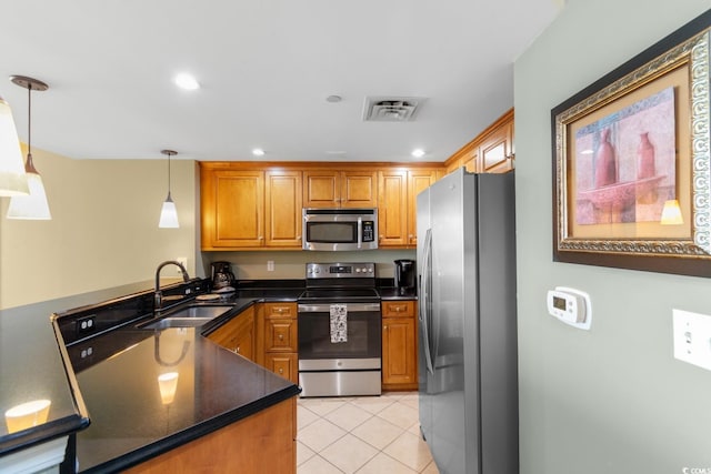 kitchen with a sink, pendant lighting, brown cabinetry, and stainless steel appliances