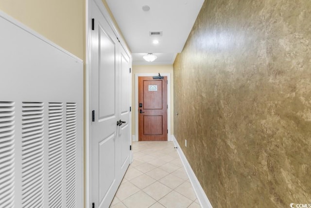 hall featuring a heating unit, baseboards, and light tile patterned floors