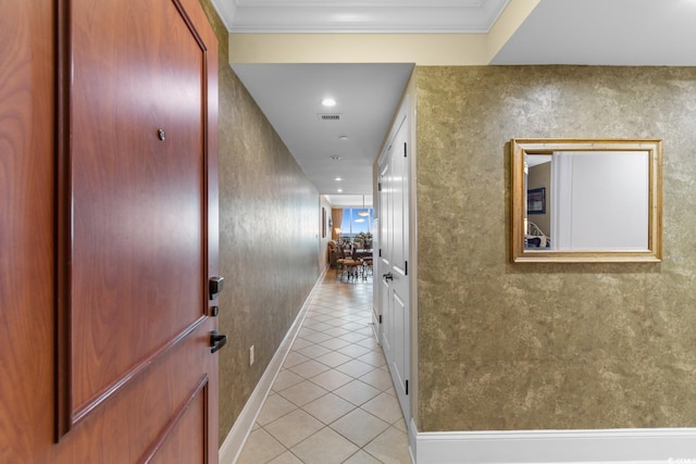 hall featuring baseboards, visible vents, ornamental molding, and light tile patterned floors