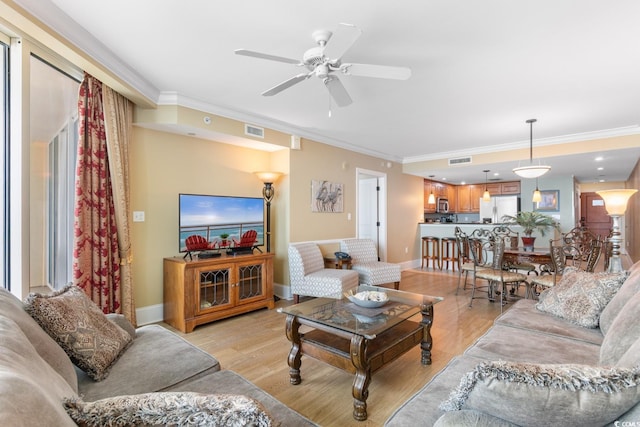 living area featuring crown molding, a ceiling fan, visible vents, and light wood-type flooring