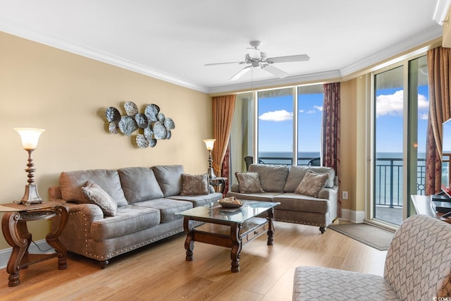 living room with a water view, ornamental molding, a ceiling fan, and light wood-type flooring