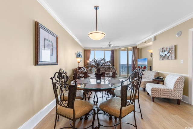 dining room featuring baseboards, ornamental molding, a ceiling fan, and light wood finished floors