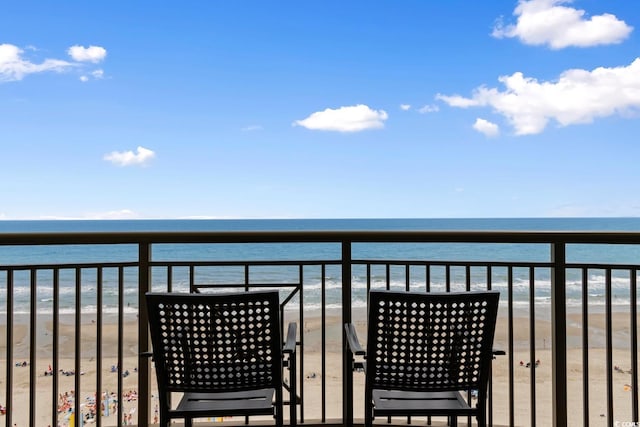 balcony with a water view and a view of the beach