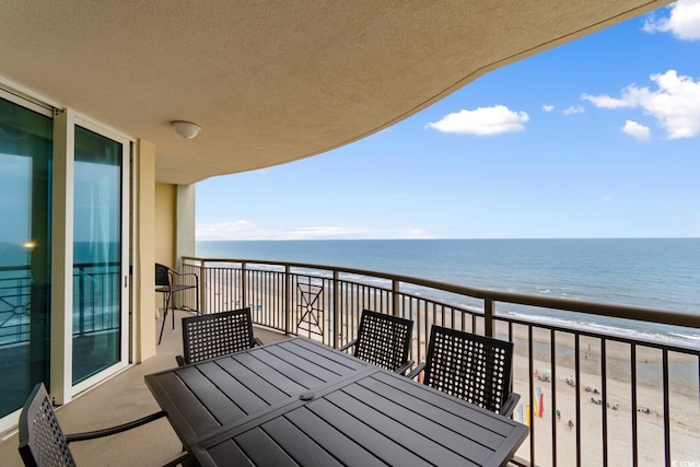 balcony with a water view, a beach view, and outdoor dining space