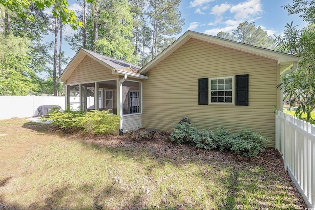 rear view of house with a fenced backyard and a sunroom