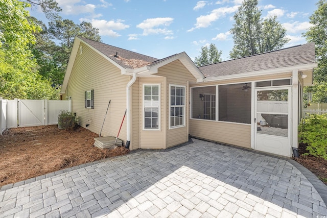 rear view of property with fence, roof with shingles, a sunroom, a gate, and a patio
