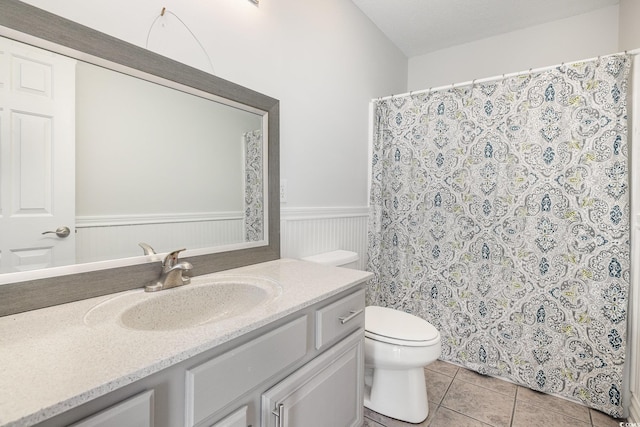bathroom with vanity, wainscoting, curtained shower, toilet, and tile patterned floors
