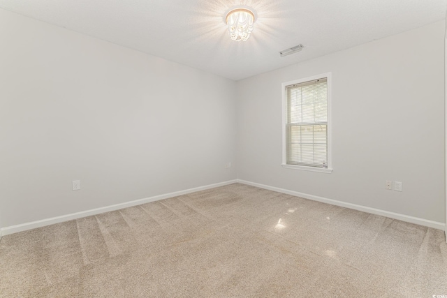 empty room with baseboards, visible vents, and carpet
