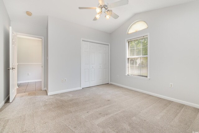 unfurnished bedroom with carpet floors, baseboards, lofted ceiling, and a closet
