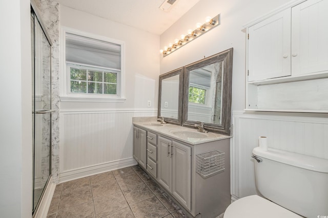 full bathroom featuring a sink, wainscoting, toilet, and a healthy amount of sunlight