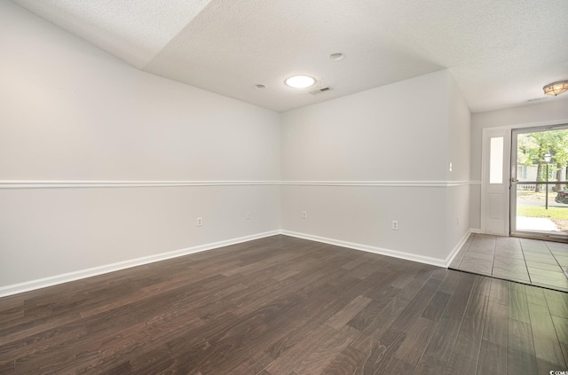 spare room featuring a textured ceiling, baseboards, wood finished floors, and visible vents