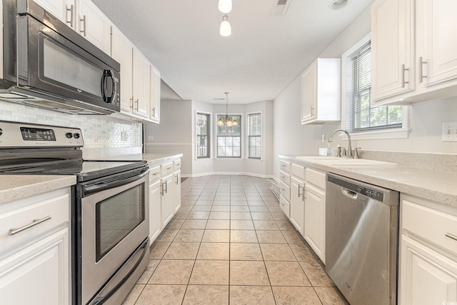 kitchen featuring backsplash, stainless steel appliances, white cabinets, and a sink