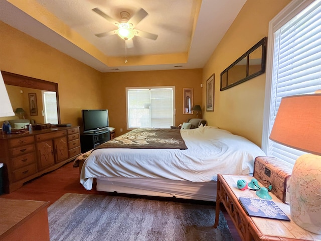 bedroom featuring a tray ceiling, ceiling fan, and wood finished floors