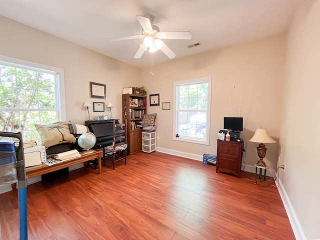 office featuring baseboards, ceiling fan, wood finished floors, and visible vents
