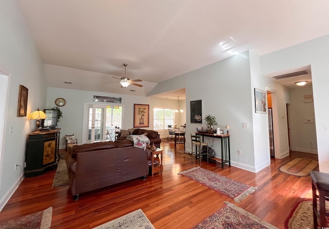 living room featuring baseboards, visible vents, wood finished floors, and ceiling fan with notable chandelier