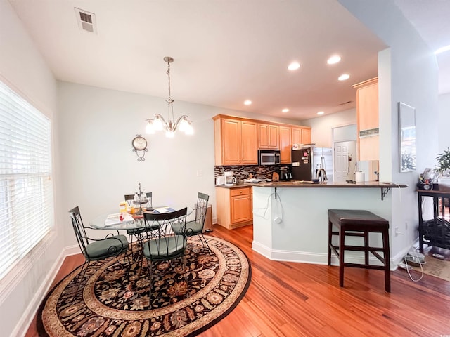 kitchen featuring dark countertops, stainless steel fridge with ice dispenser, light wood-style floors, light brown cabinets, and visible vents