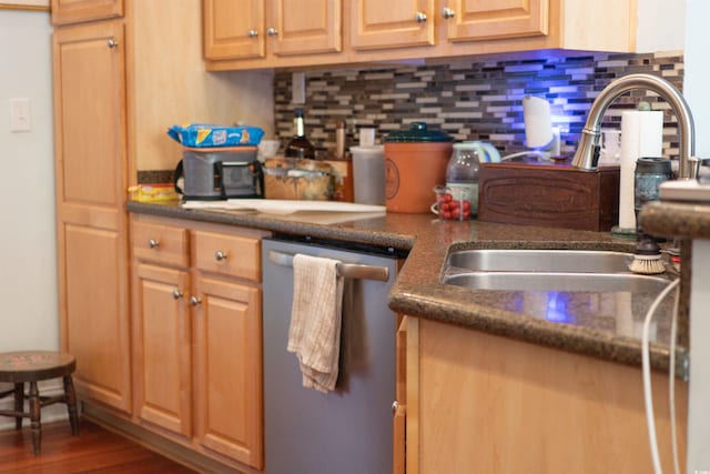 kitchen with stainless steel dishwasher, a sink, backsplash, and wood finished floors