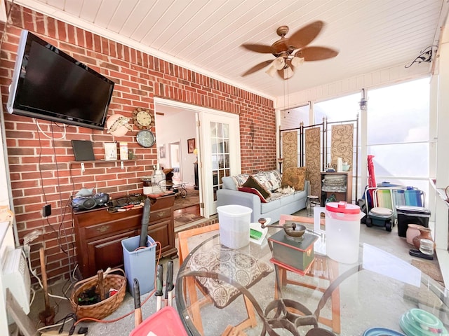interior space with ornamental molding, ceiling fan, and brick wall