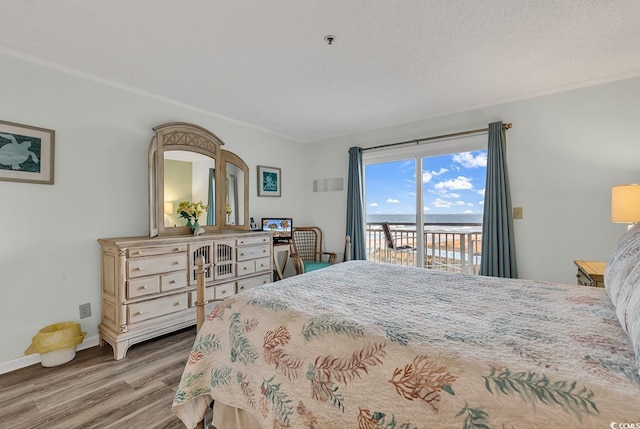 1581 S Waccamaw Dr Unit 302, Garden City Beach, SC 29576 - bedroom featuring ornamental molding, wood finished floors, baseboards, access to outside, and a water view