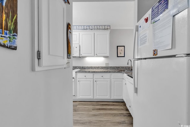 1581 S Waccamaw Dr Unit 302, Garden City Beach, SC 29576 - kitchen featuring a sink, white appliances, light wood-style flooring, dark stone countertops, and white cabinetry