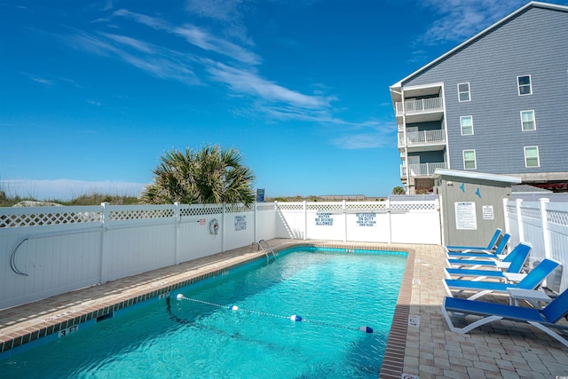 community pool with fence and a patio