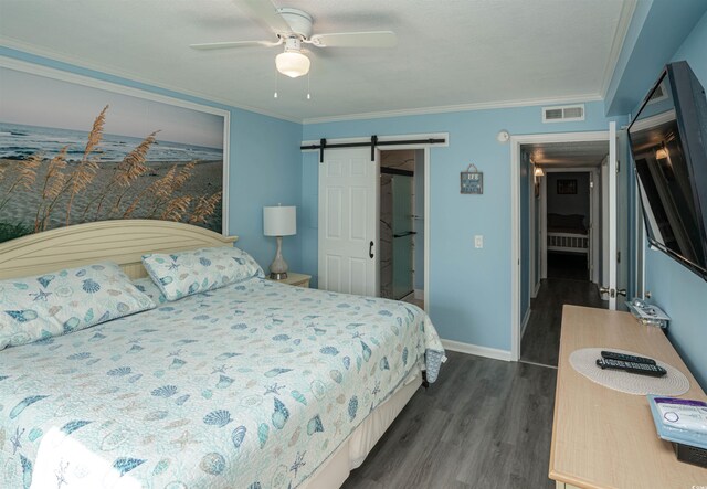 bedroom featuring dark wood-style flooring, visible vents, a barn door, baseboards, and ornamental molding
