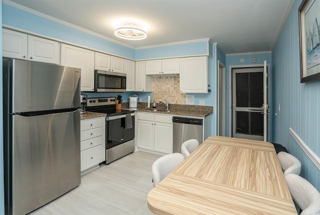 kitchen featuring a sink, appliances with stainless steel finishes, ornamental molding, and white cabinetry