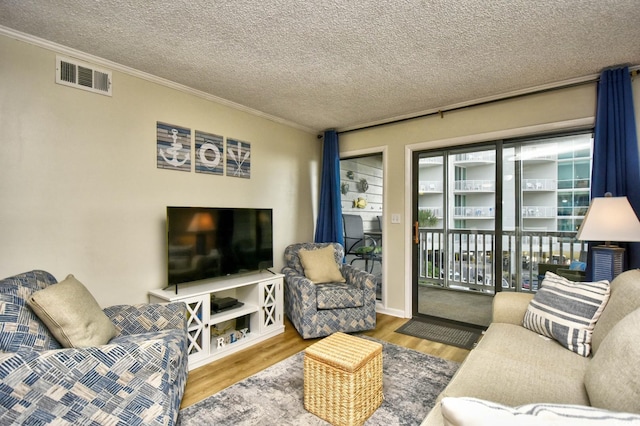 living area featuring visible vents, ornamental molding, and wood finished floors