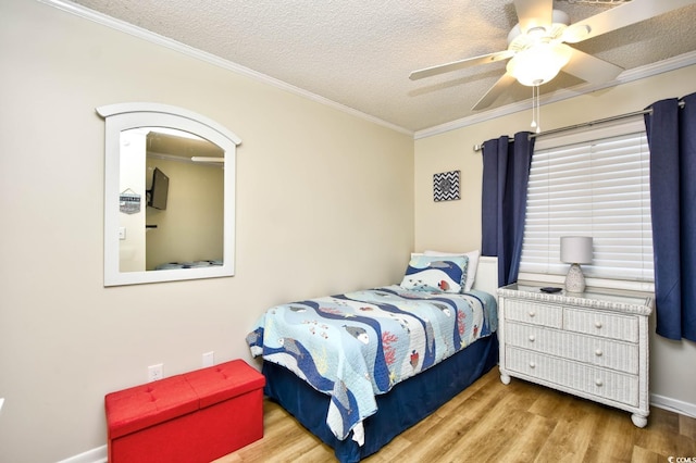 bedroom featuring a ceiling fan, a textured ceiling, wood finished floors, baseboards, and ornamental molding