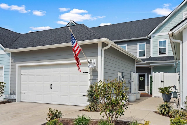 view of front of property featuring an attached garage, a shingled roof, and driveway
